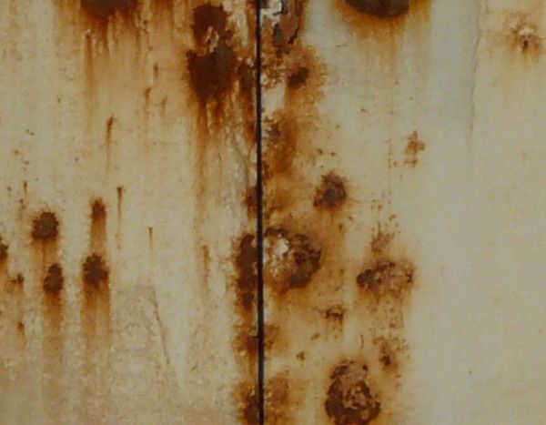 White metal texture covered by many small red spots and patches of rust.